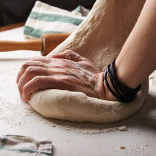 person making dough beside brown wooden rolling pin